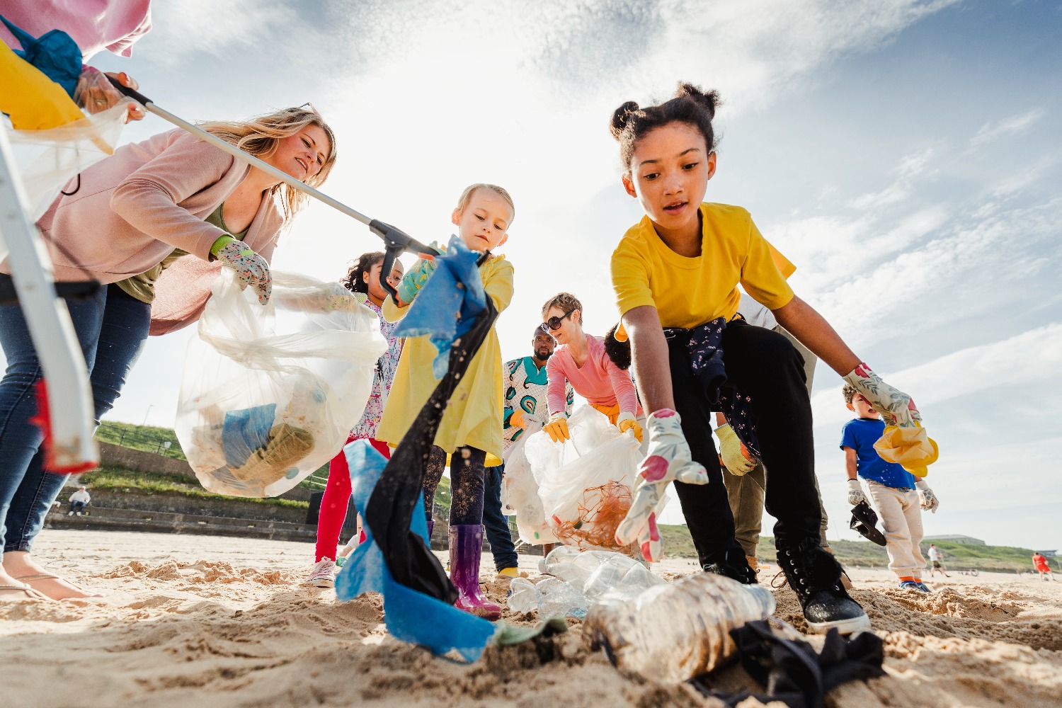 Kinderen rapen zwerfvuil op het strand.