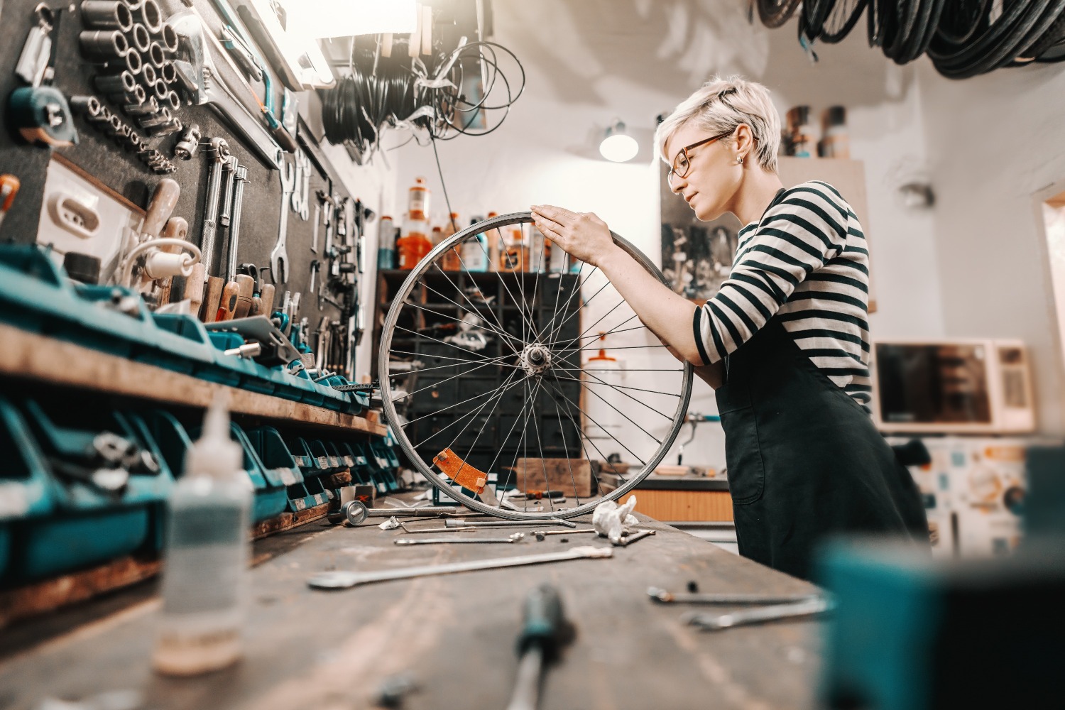 Vrouwelijke werknemer houdt fietswiel vast en repareert terwijl zij in een fietswerkplaats staat